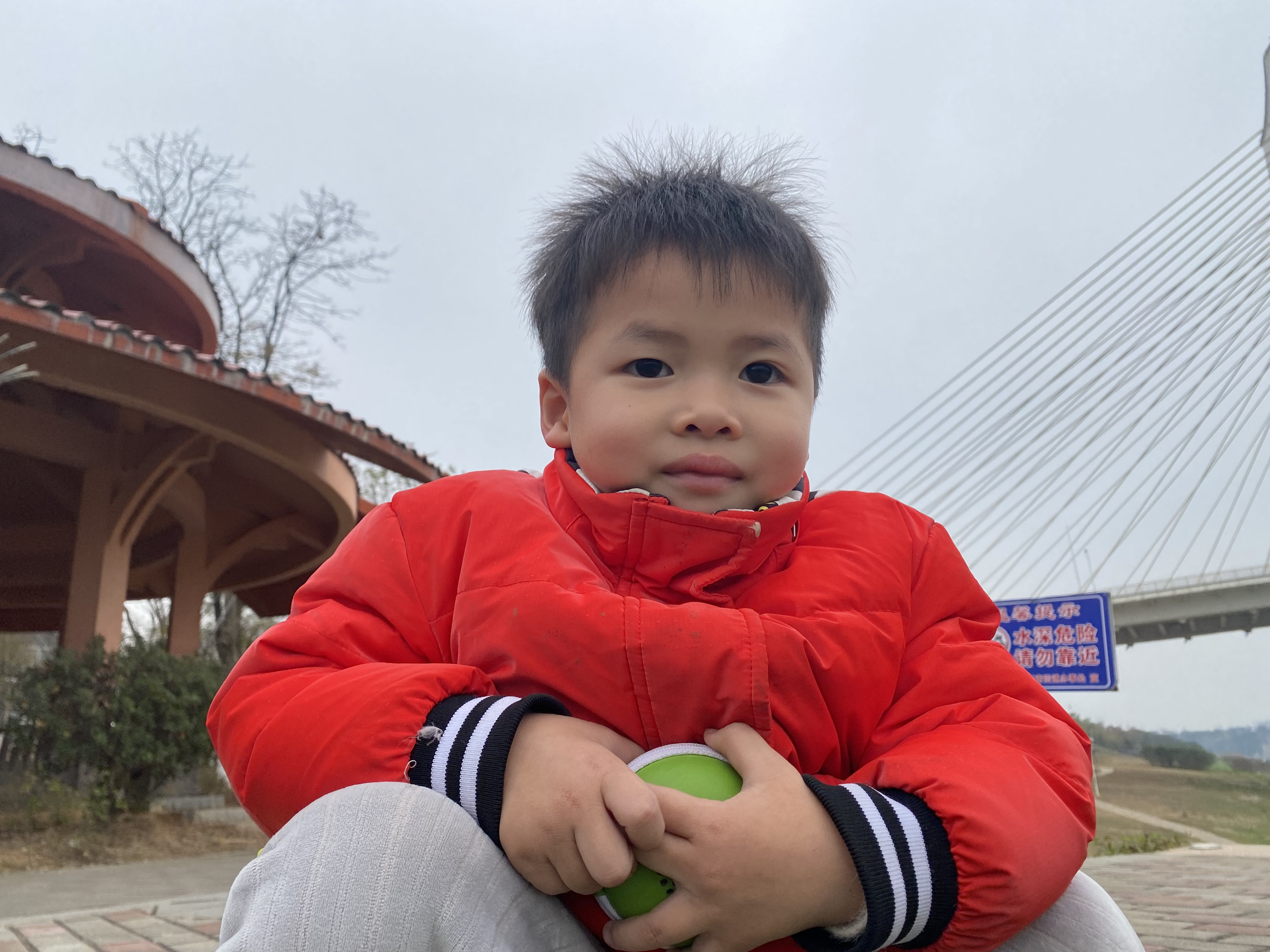 Sven’s young child in a bright red coat beside a bridge